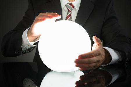 44304428 - close-up of businessman predicting future with crystal ball at desk