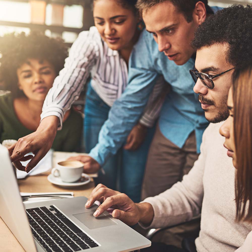 Diverse group of professionals collaborating around a laptop.