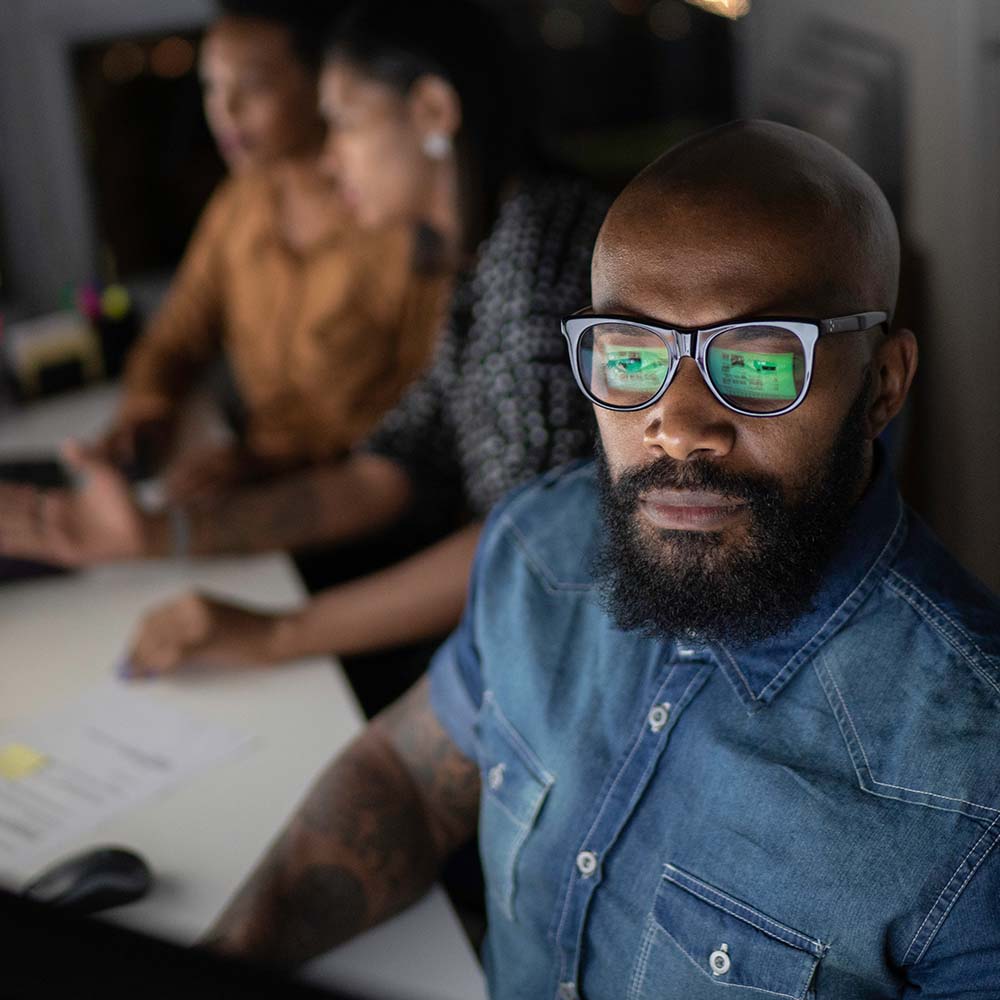 5 Ways Manufacturers Can Boost Agility - Photo of man working intently with team collaborating int the background