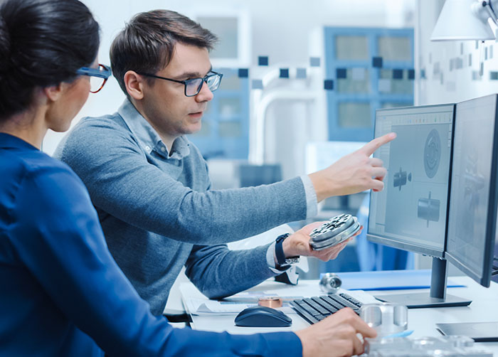 Image-Engineers holding a Machine Part Comparing it to one on Computer Screen