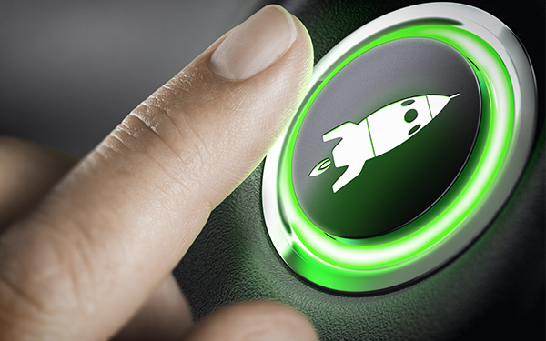 Image-Close up of a finger pressing a launch button with a rocket icon on it