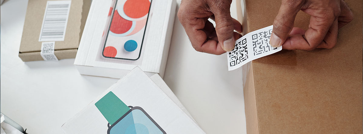 Image-Person applying QR codes to electronics packaging