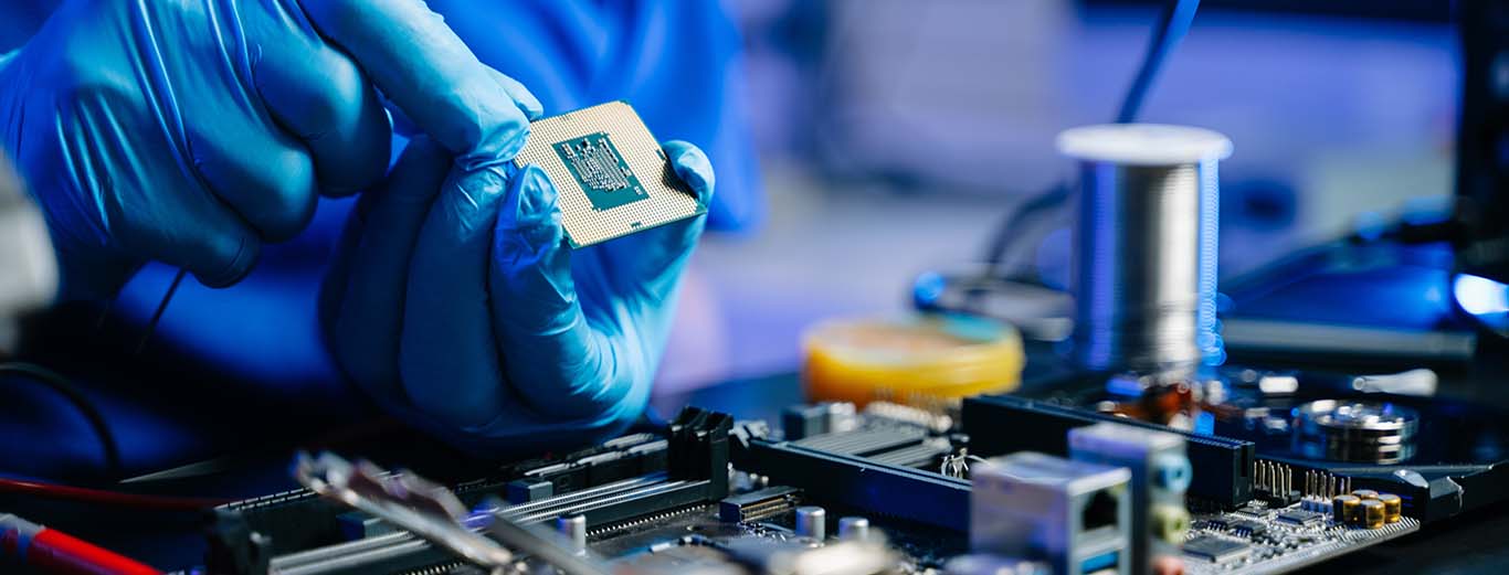 Image-Closeup of tech/engineer holding a chipset while working on a circuit board