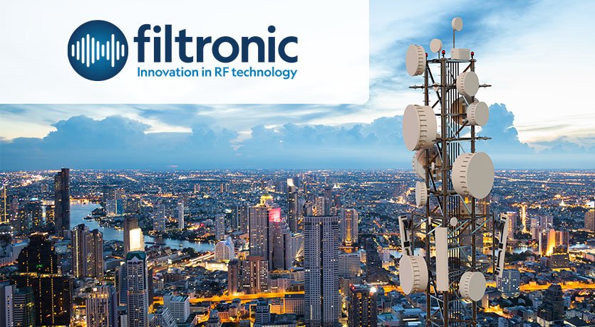 Logotipo de Filtronic superpuesto sobre un paisaje urbano centrado en una torre de comunicaciones.