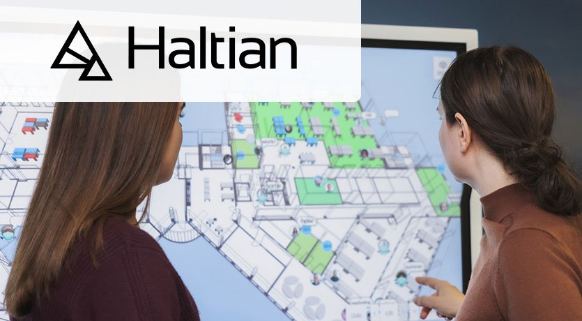 Logotipo de Haltian sobre la imagen de unos compañeros de trabajo utilizando el software de Haltian para mostrar un plano.