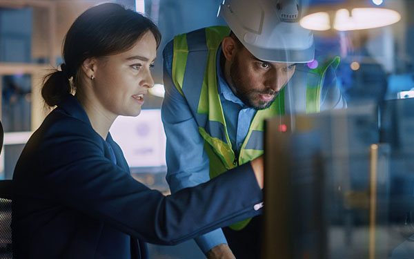 Image-Specialists collaborating at a computer in factory setting