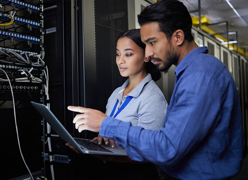 Image-IT engineers collaborating, holding laptop, in server room