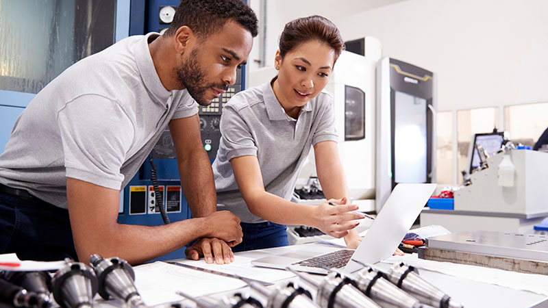 Image-Engineers discussing product/parts while referring to a a laptop in a manufacturing setting