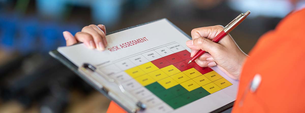 Image-Person using a pen to mark "High risk" level on the risk assessment matrix table.