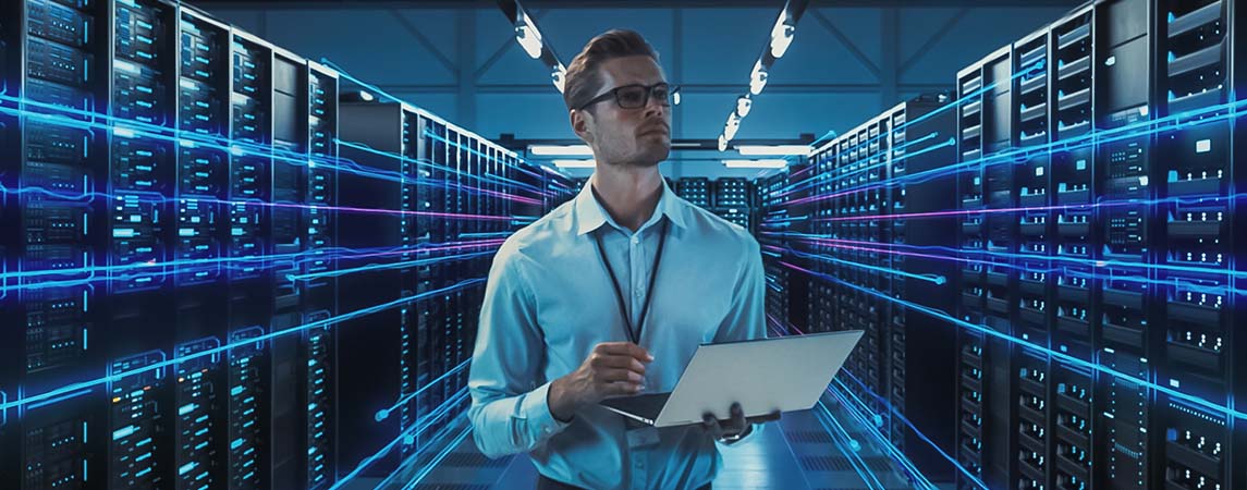 Image-IT professional holding laptop in massive high-tech server warehouse.
