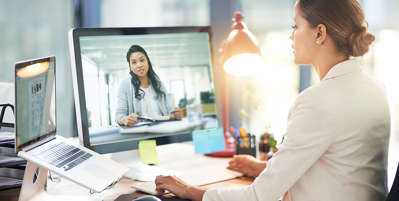 Image-two colleagues video chatting with each other on a computer at work